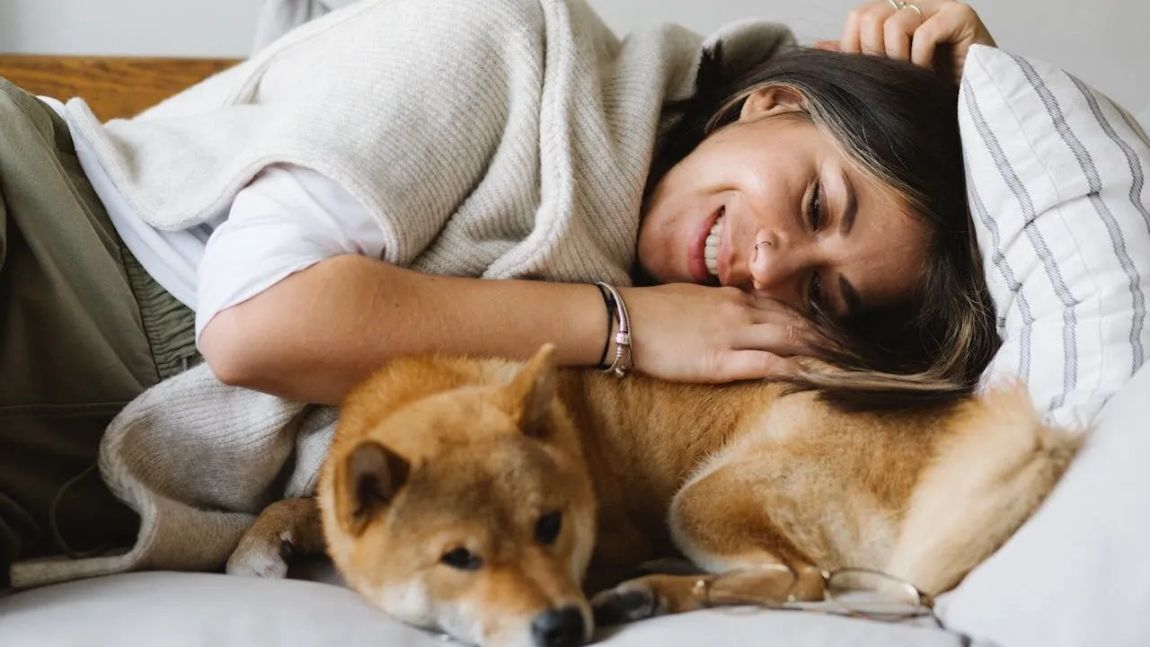 appy woman lying on sofa with cute purebred dog