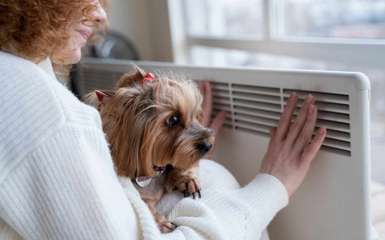 smiley woman sitting near heater with dog